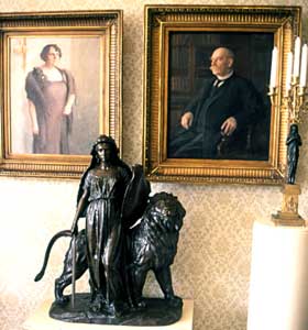 Ukko-Pekka ja hänen vaimonsa tauluna huoneen seinällä. Etualla olevan Suomen laki nimisen patsaan alkuperäinen versio seisoo presidentin valtiosalissa.