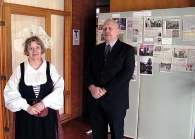 Puheenjohtaja Jyrki Sahari ja sihteeri Auli Pitkänen vastaanottavat vieraita lehtileiketaulun vieressä.